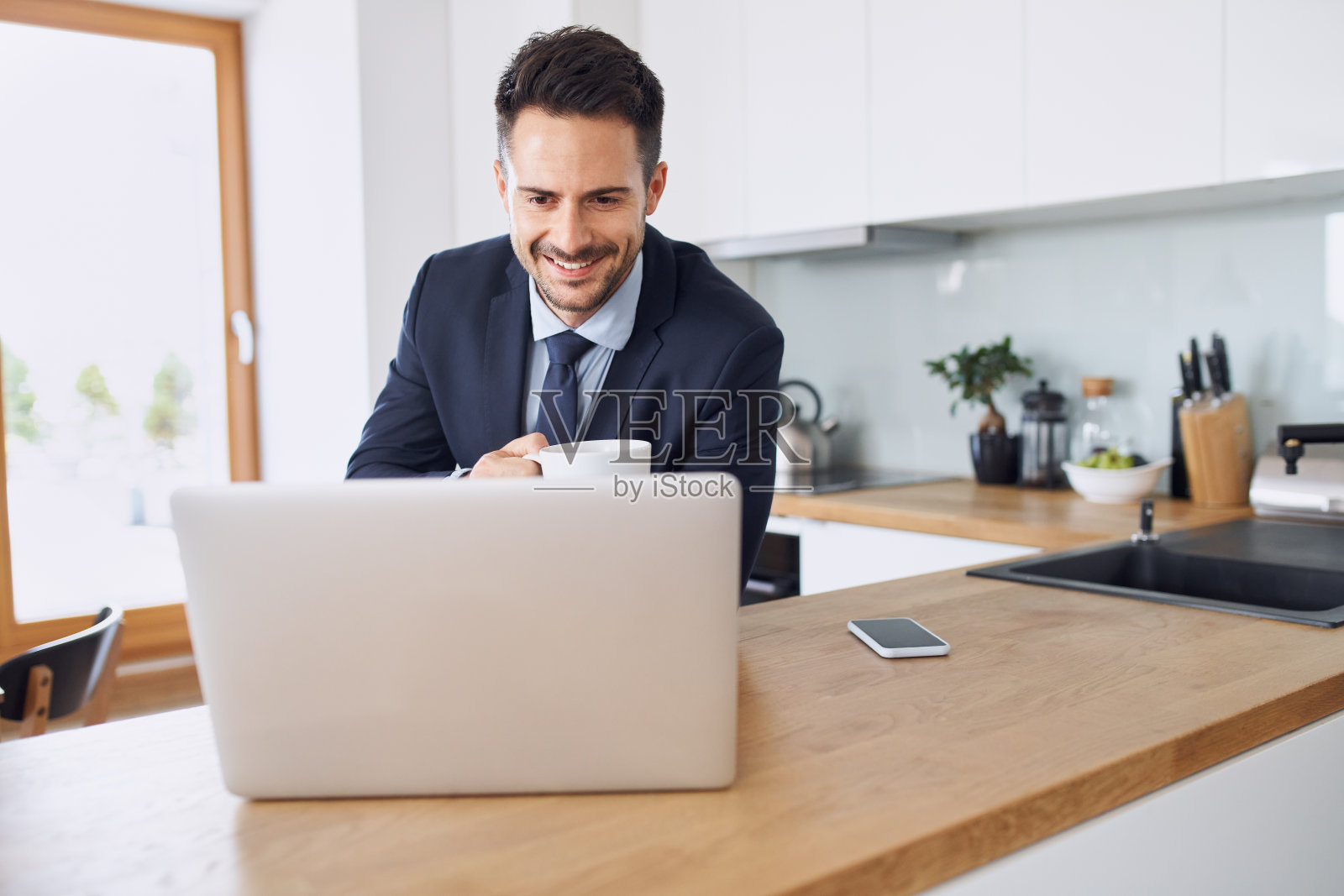 商人在家里用笔记本电脑,在厨房喝咖啡照片摄影图片
