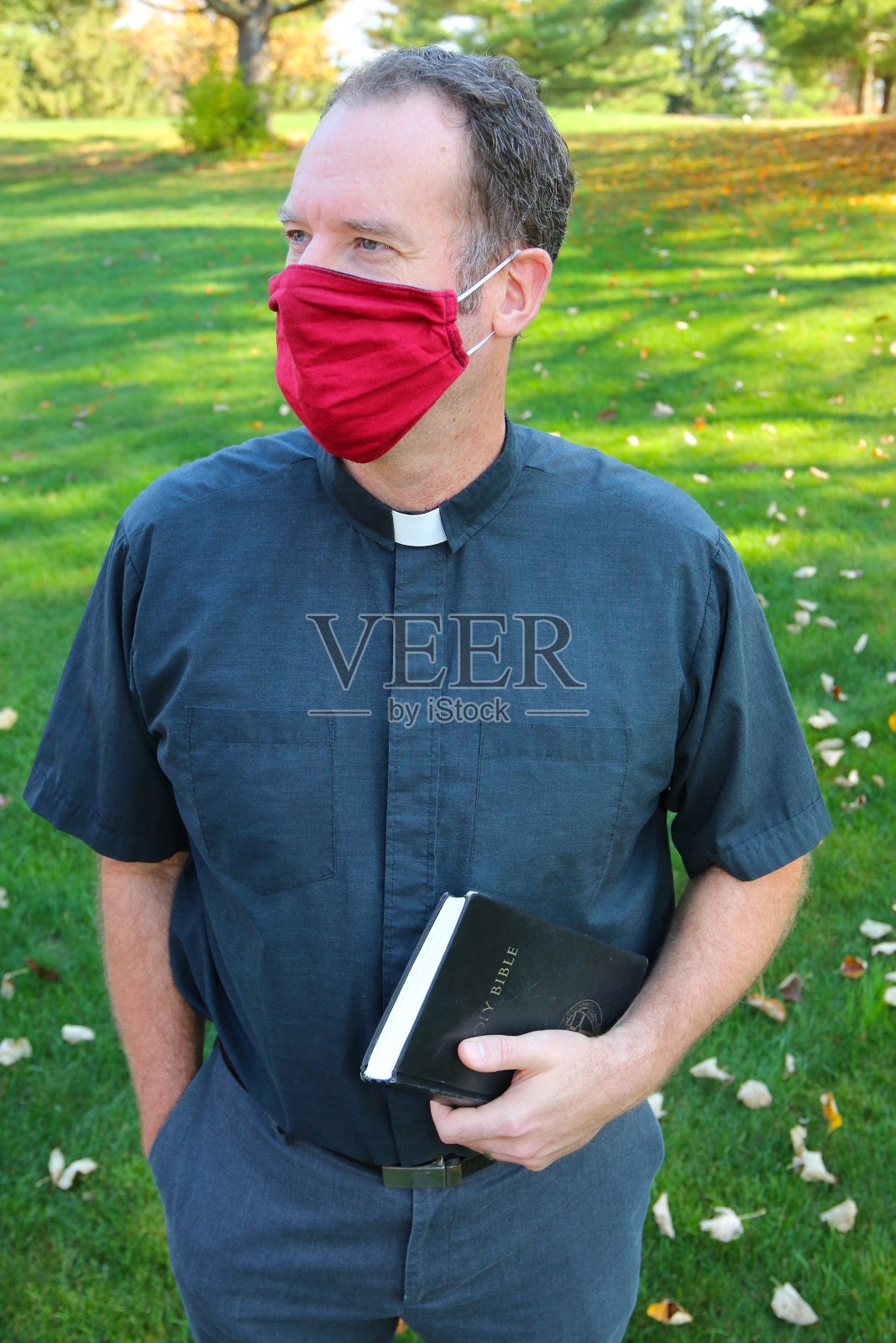 牧师戴着带圣经的红色面具照片摄影图片