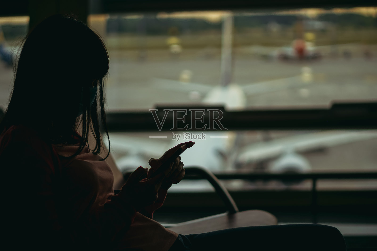病毒:在机场戴着医用口罩等待飞机航班的女人照片摄影图片