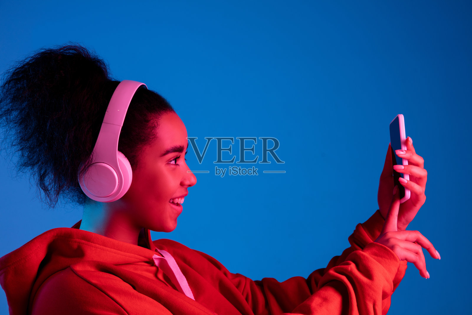 非裔美国妇女的肖像被隔离在彩色霓虹灯下的蓝色画室背景上照片摄影图片