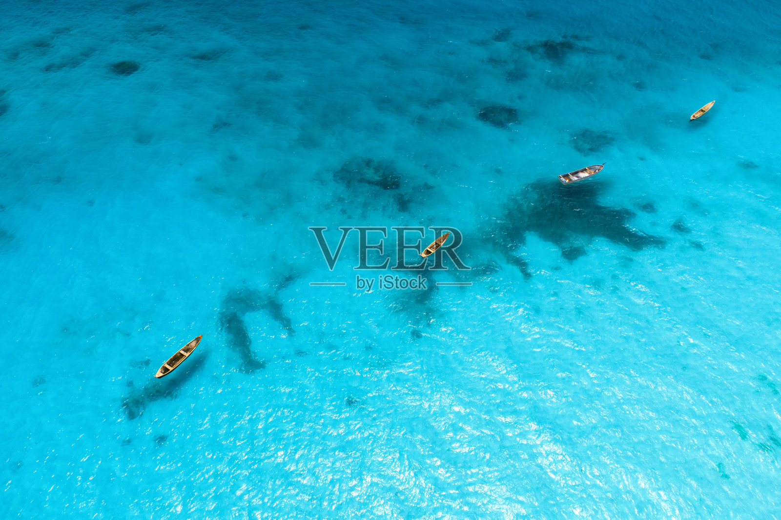 鸟瞰图的渔船在清澈的蓝色的水在晴朗的一天在夏天。从船上俯瞰沙滩。非洲桑给巴尔的印度洋。风景有独木舟和清澈的大海。旅行照片摄影图片