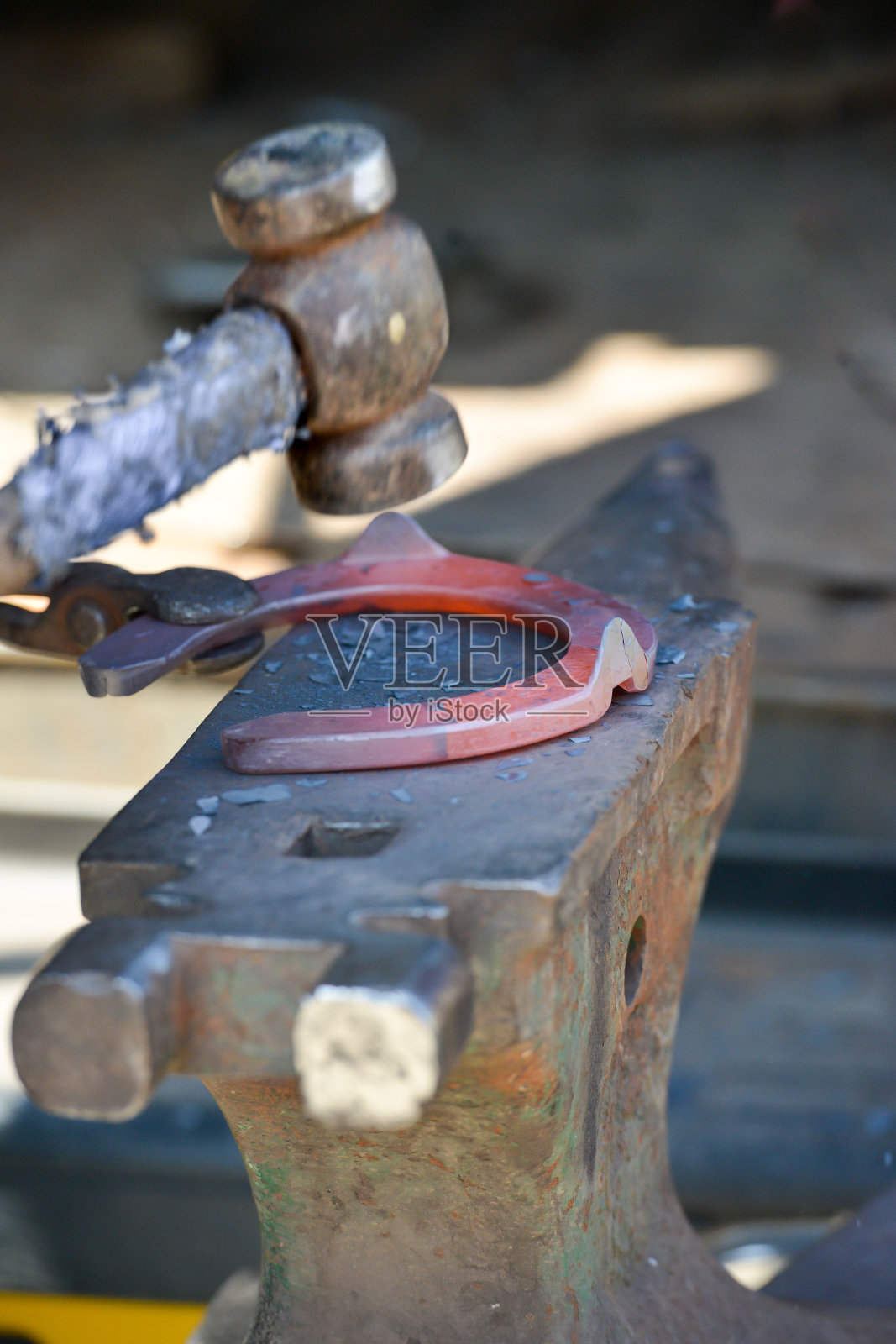 法里尔用铁锤和铁砧塑造一个红色的热马蹄。照片摄影图片