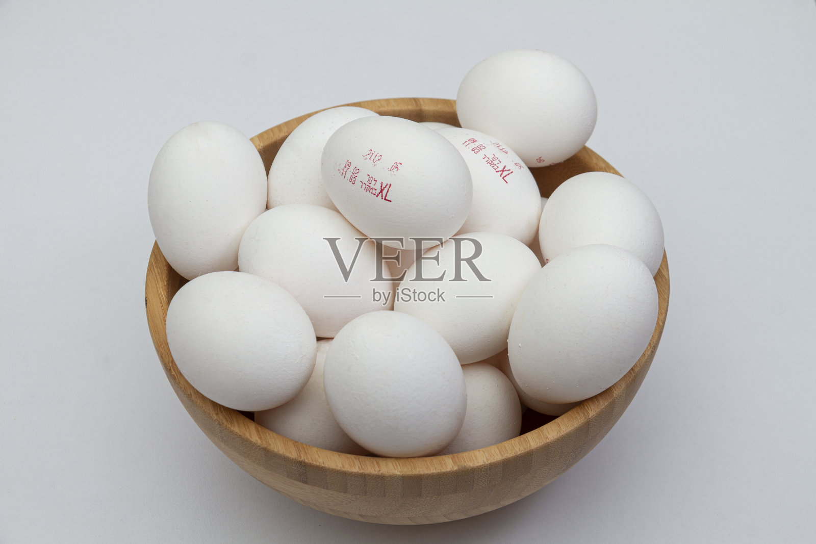 浅色桌子上木碗里的鸡蛋照片摄影图片