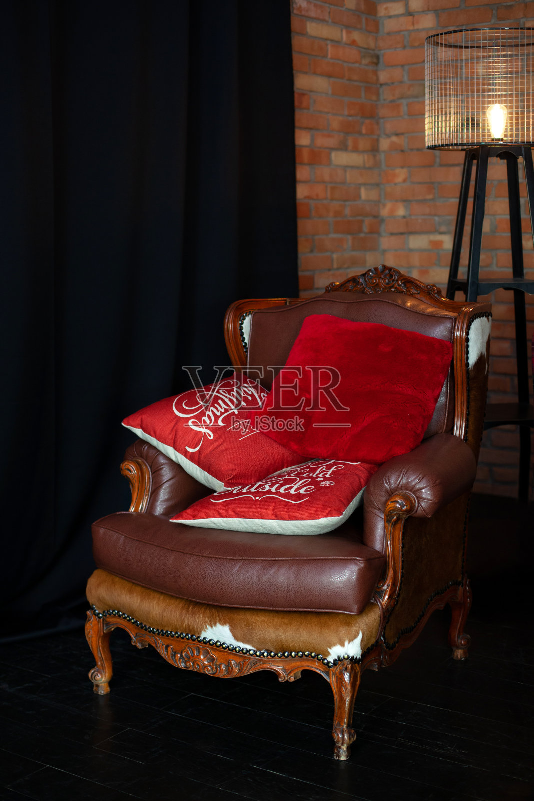 室内装饰时尚,真皮扶手椅,红色砖墙。舒适的装饰客厅与落地灯。圣诞假期的概念。经典旧棕色沙发上的枕头。阁楼风格的客厅照片摄影图片
