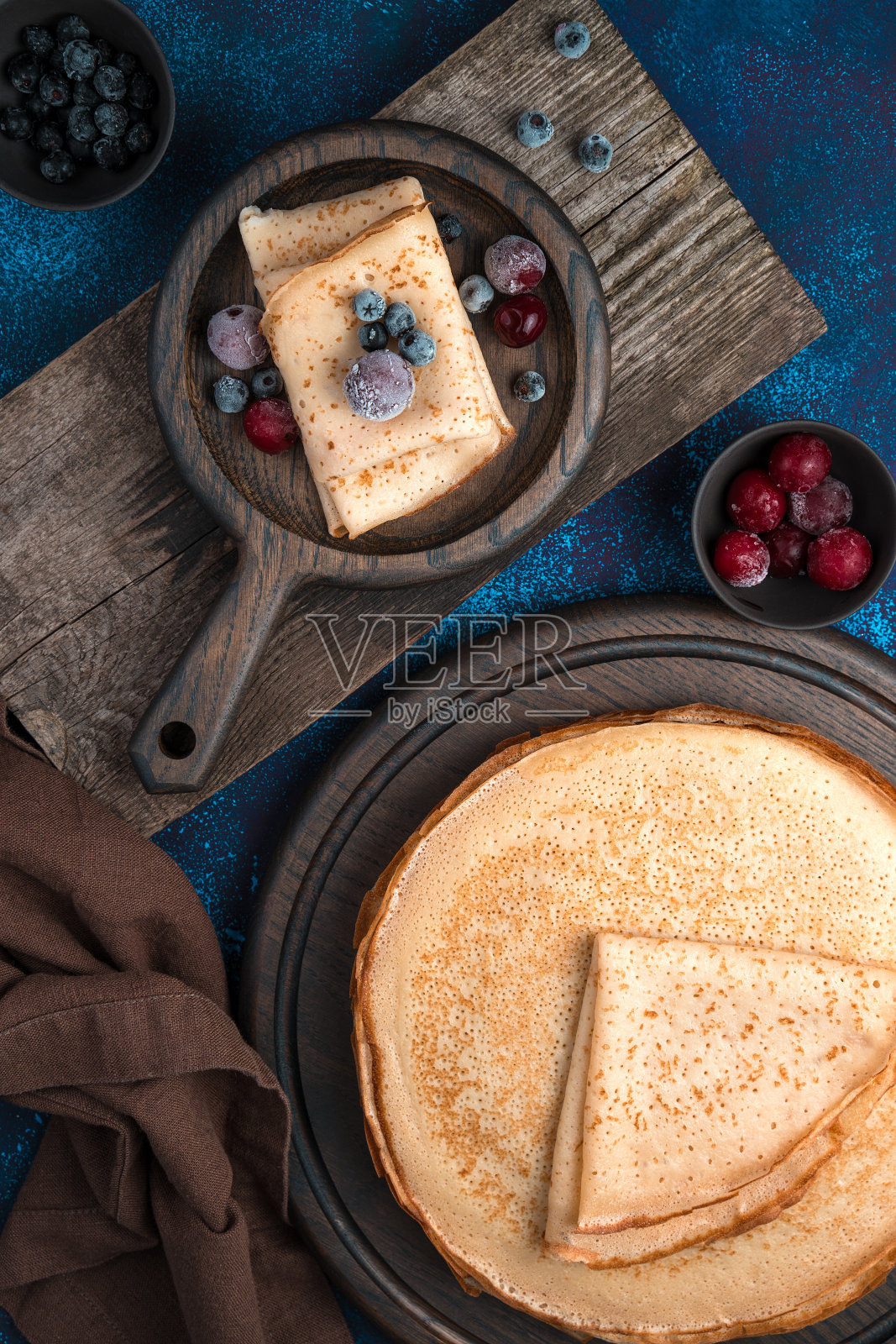 蓝色背景的木板上的煎饼和冰冻的浆果照片摄影图片