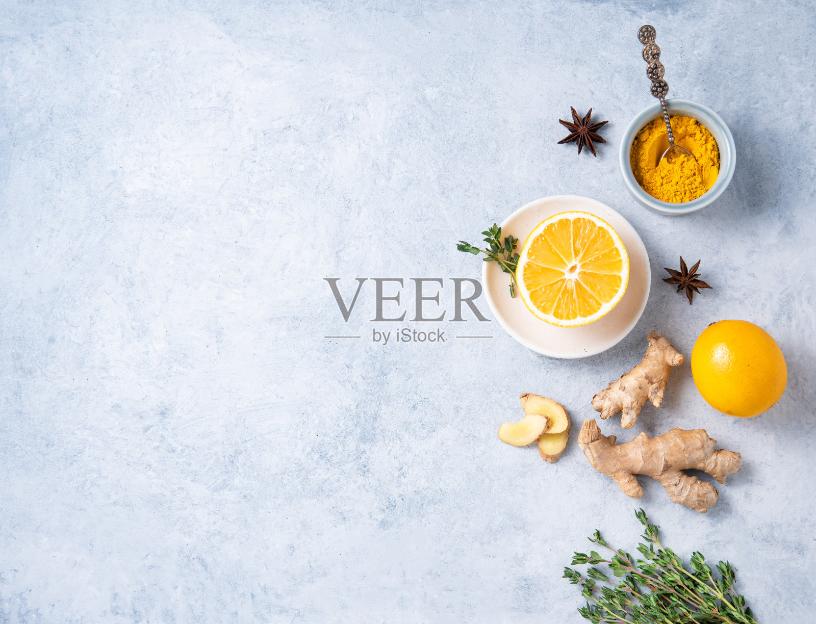 阿育吠陀饮料的配方。姜黄粉,生姜,百里香,八角和柠檬在蓝色背景照片摄影图片