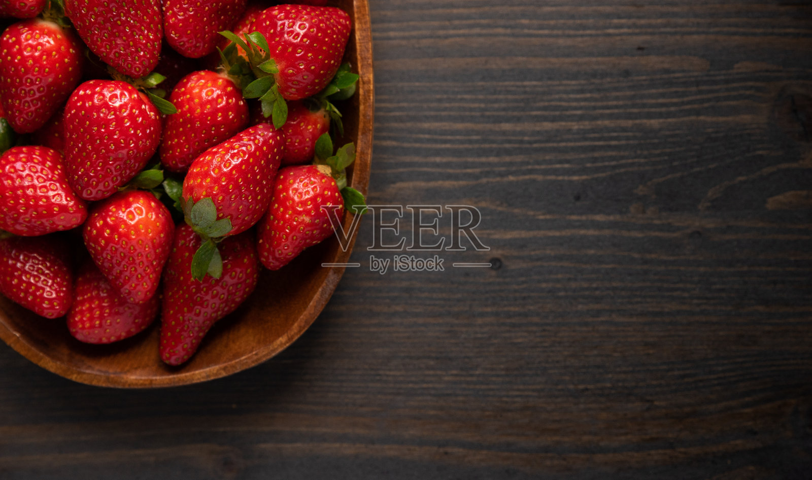 草莓装在木制的盘子里,有木制的背景。平铺与拷贝空间照片摄影图片