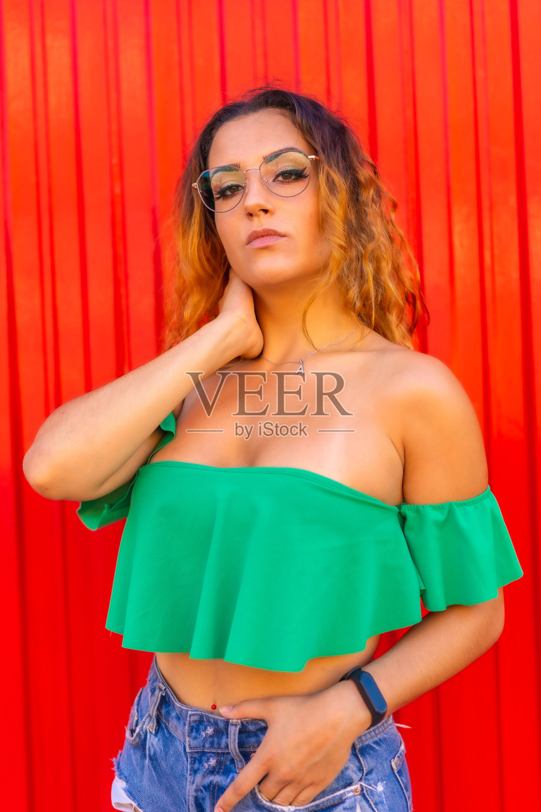 生活方式,白种人金发女孩在绿色t恤和透明看到眼镜上的红色背景。带着诱人的夏日照片照片摄影图片