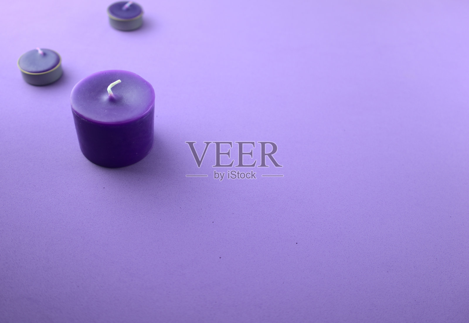 桌上放着紫色、薰衣草色的蜡烛。芳香疗法,水疗,按摩,放松或改善心理健康的概念。最小的组合与复制空间。照片摄影图片