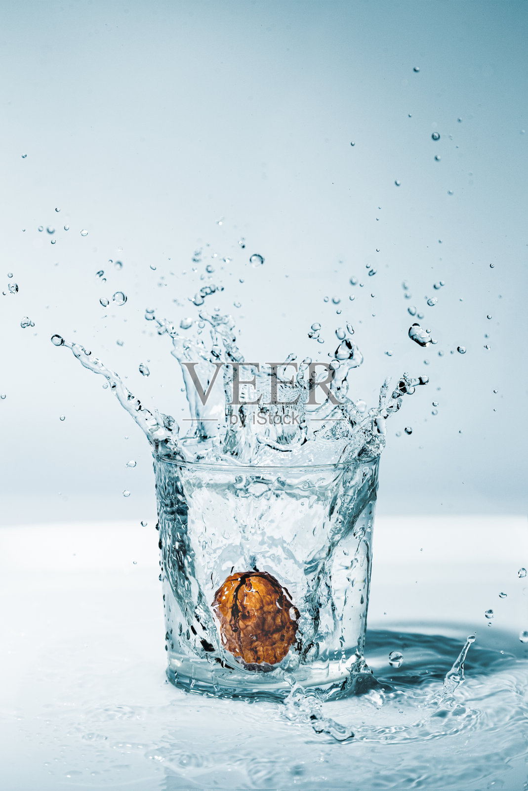 一颗溅在一杯水里的核桃照片摄影图片