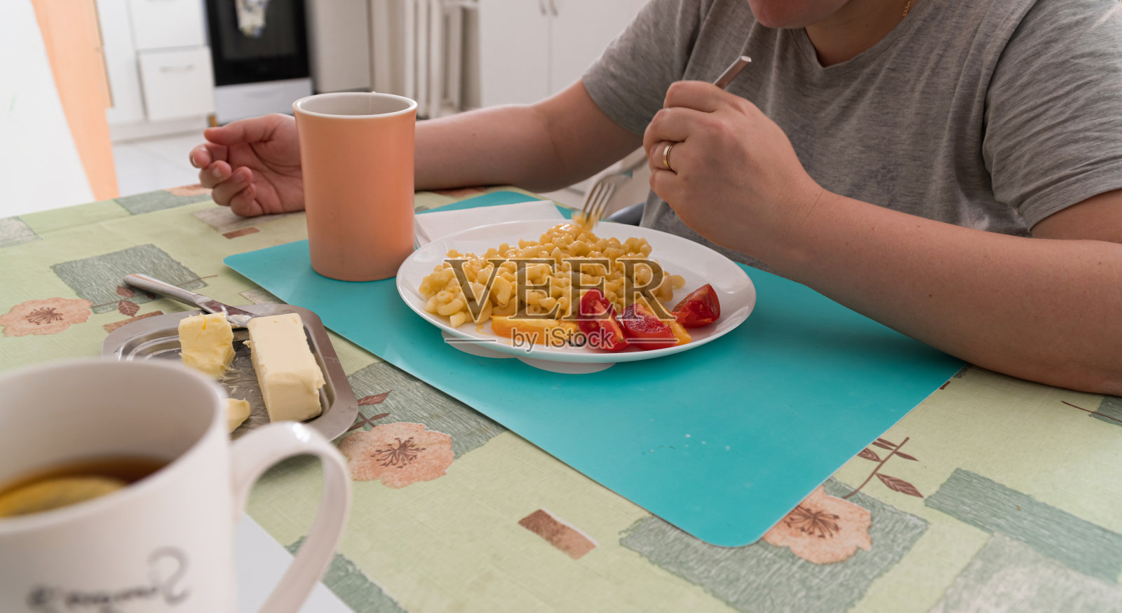 在家里吃奶酪和樱桃番茄意大利面的女人。本空间照片摄影图片
