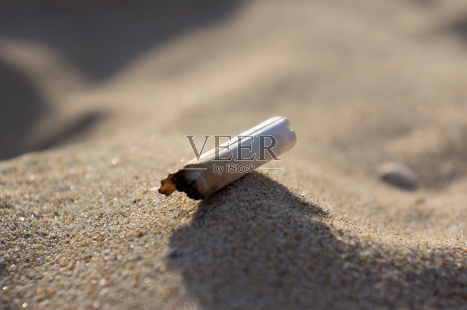 沙地上的烟头。人类的污染照片摄影图片