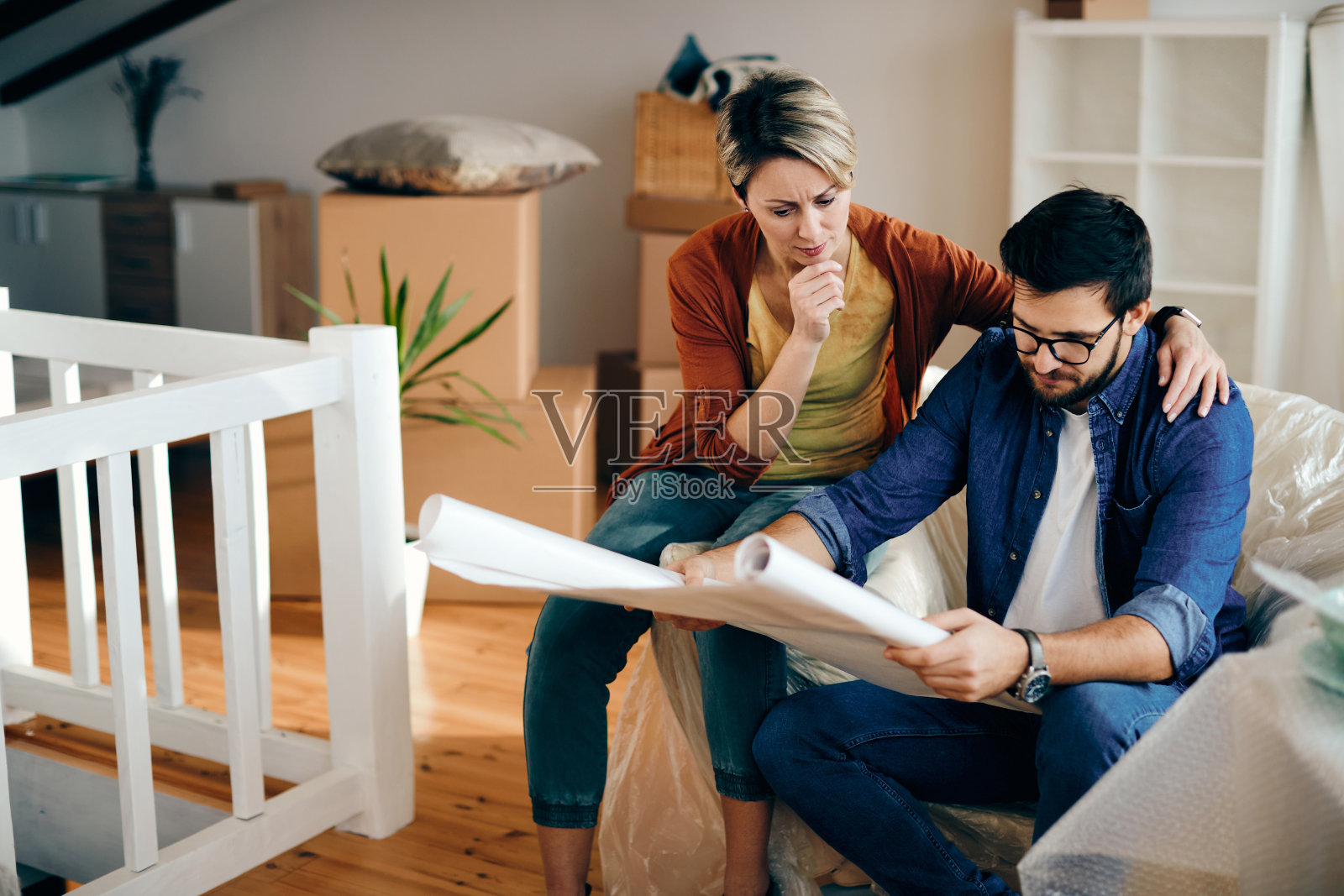 一对沉思的夫妇正在看他们新公寓的设计图。照片摄影图片