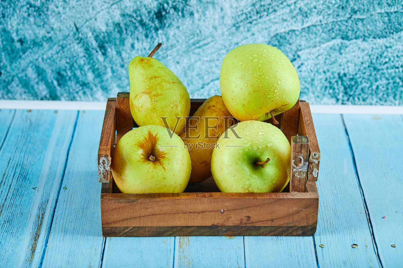新鲜的苹果和梨在一个木盒子里在蓝色的背景照片摄影图片