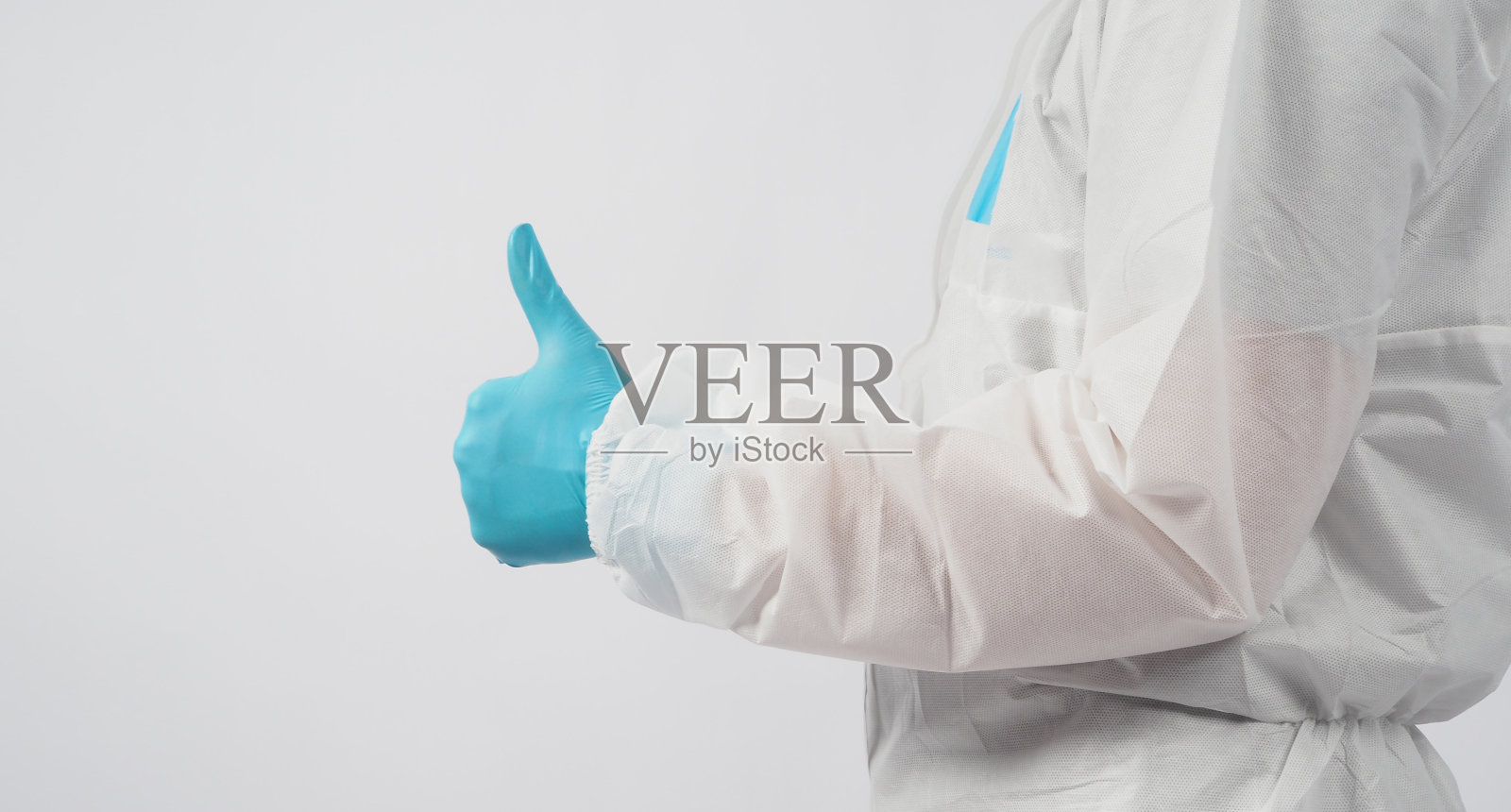 男模特穿着PPE套装,戴着面罩,在白色背景上竖起大拇指或手势。照片摄影图片