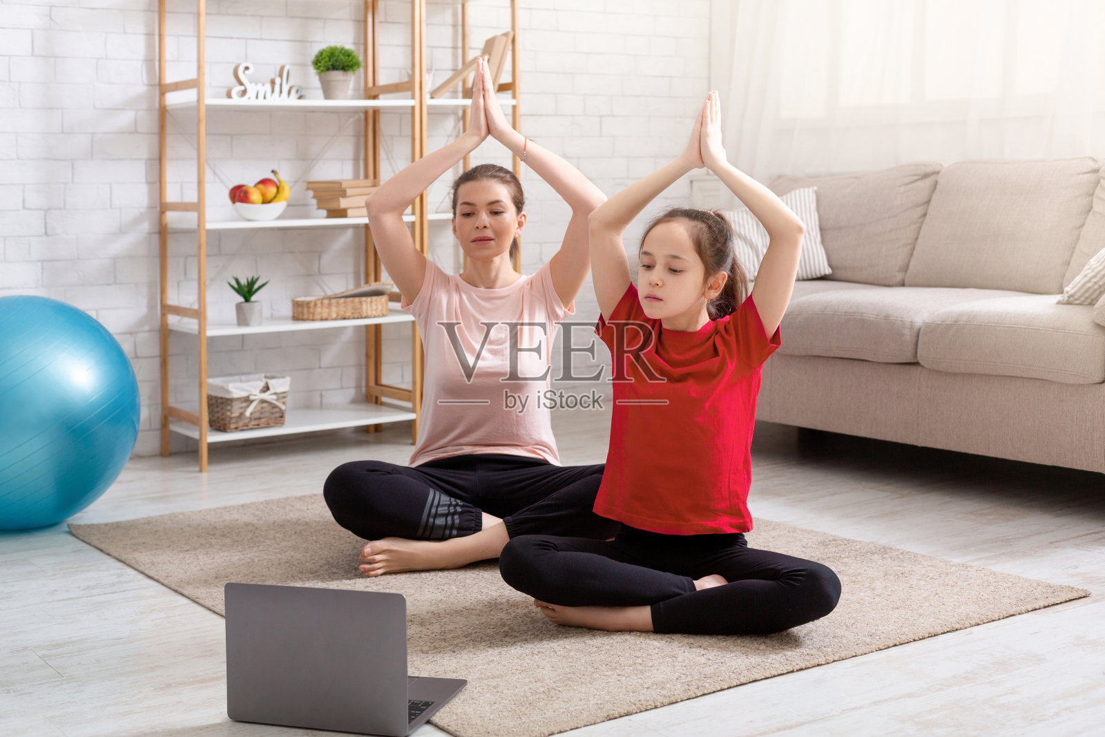国内的锻炼。年轻的运动母亲和她十几岁的女儿做瑜伽在线视频课程在家里的笔记本电脑照片摄影图片