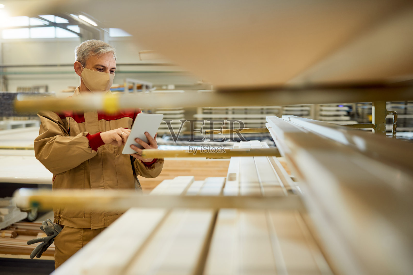 男木匠戴着防护面罩在车间触摸板上工作。照片摄影图片