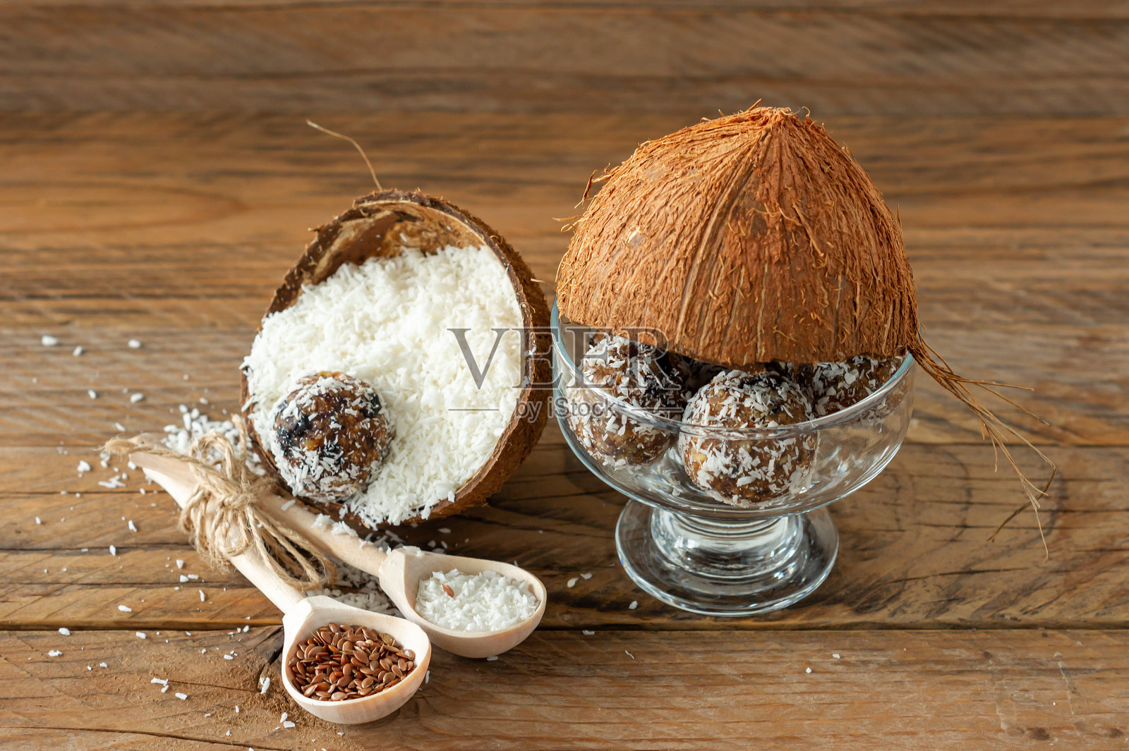 健康食品的概念。自制椰子能量球在椰子壳上的木制背景。照片摄影图片