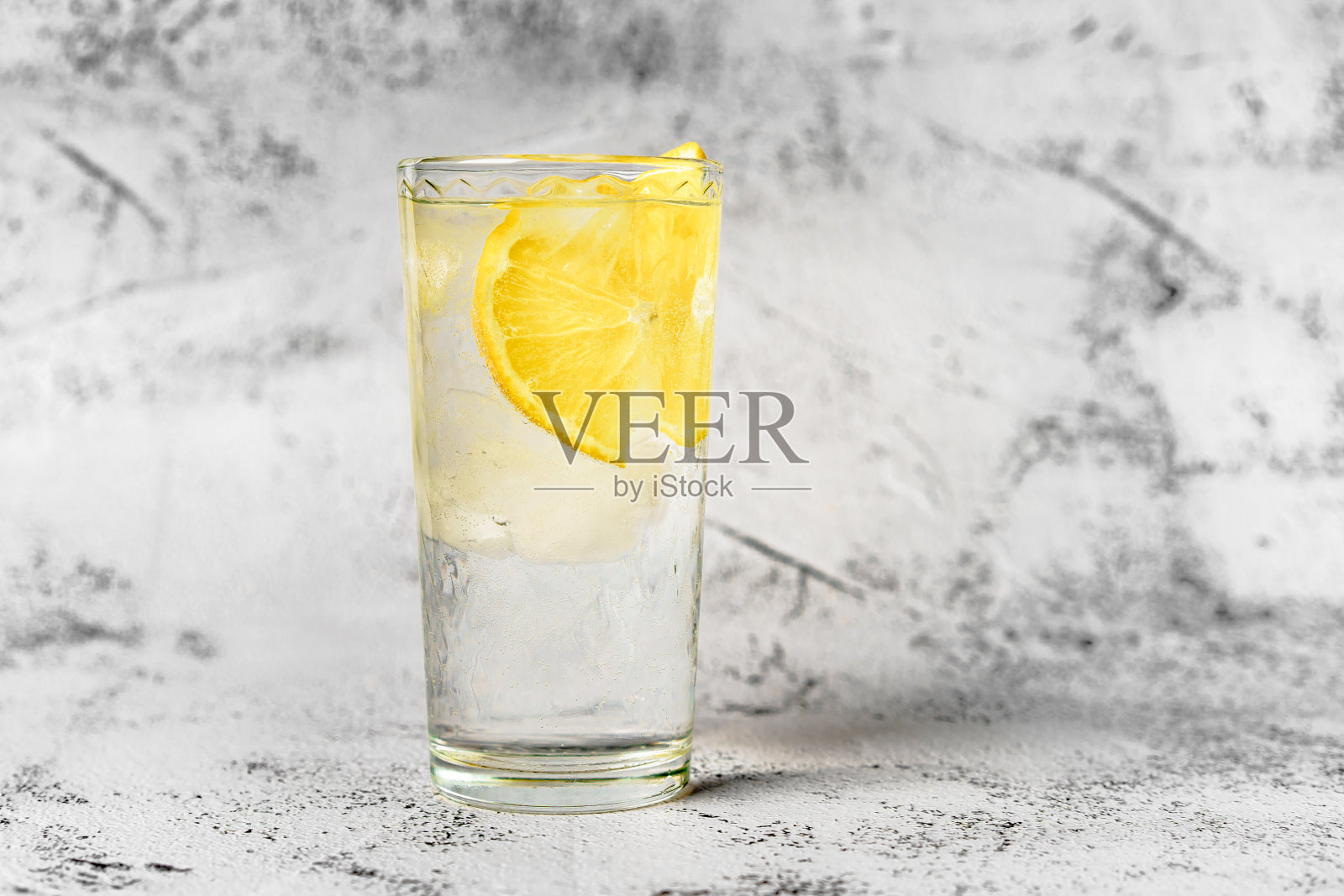 一杯在灰色背景上加冰和柠檬的水,这是一种适当的健康生活方式的概念照片摄影图片