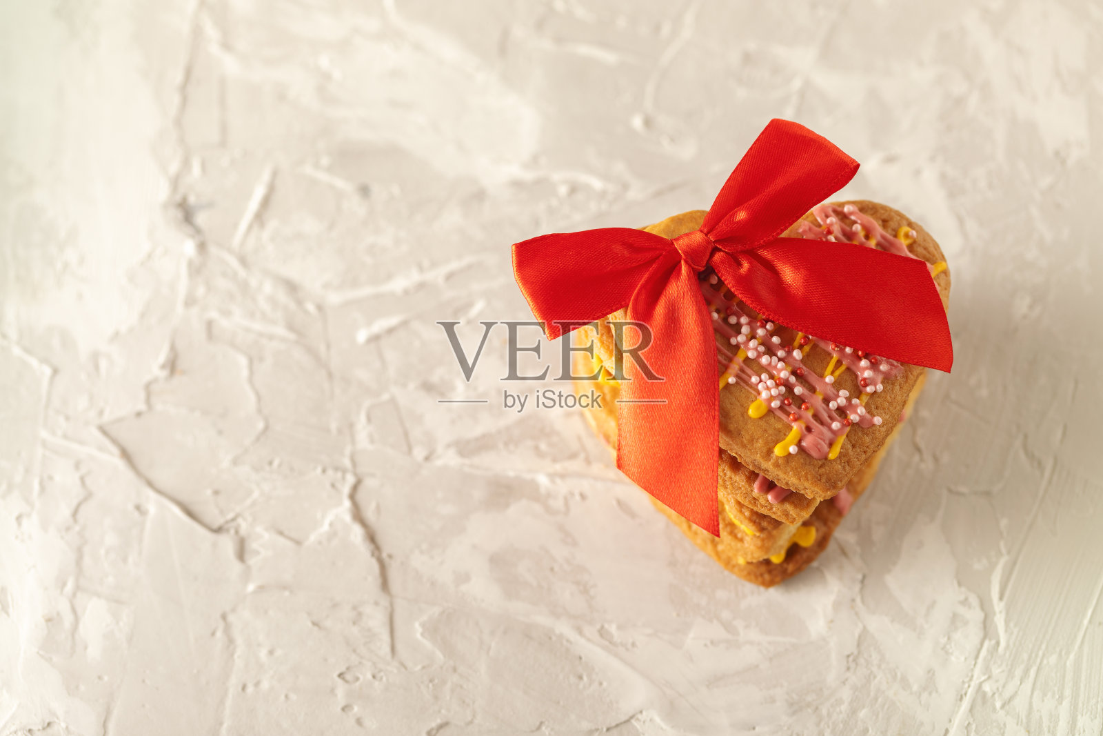 饼干心形装饰用釉带蝴蝶结的混凝土纹理背景上,放置文字糖果,甜点,节日背景照片摄影图片