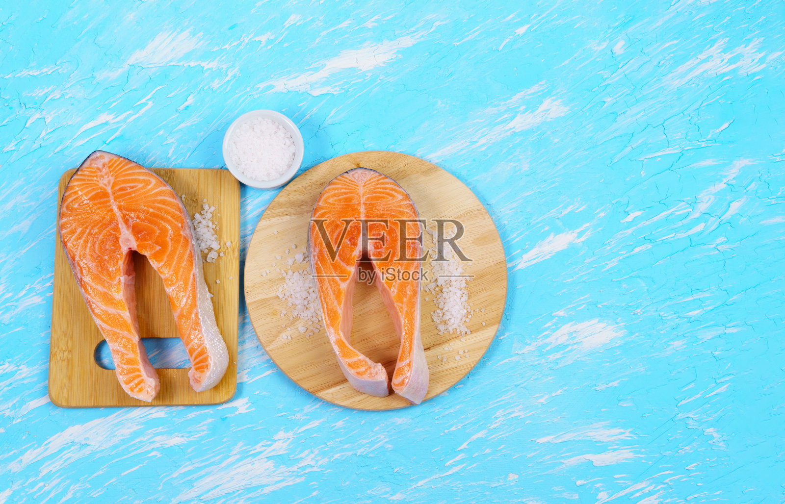 生鲑鱼牛排配柠檬,海盐和胡椒鱼在蓝色背景,俯视图。健康饮食理念。照片摄影图片