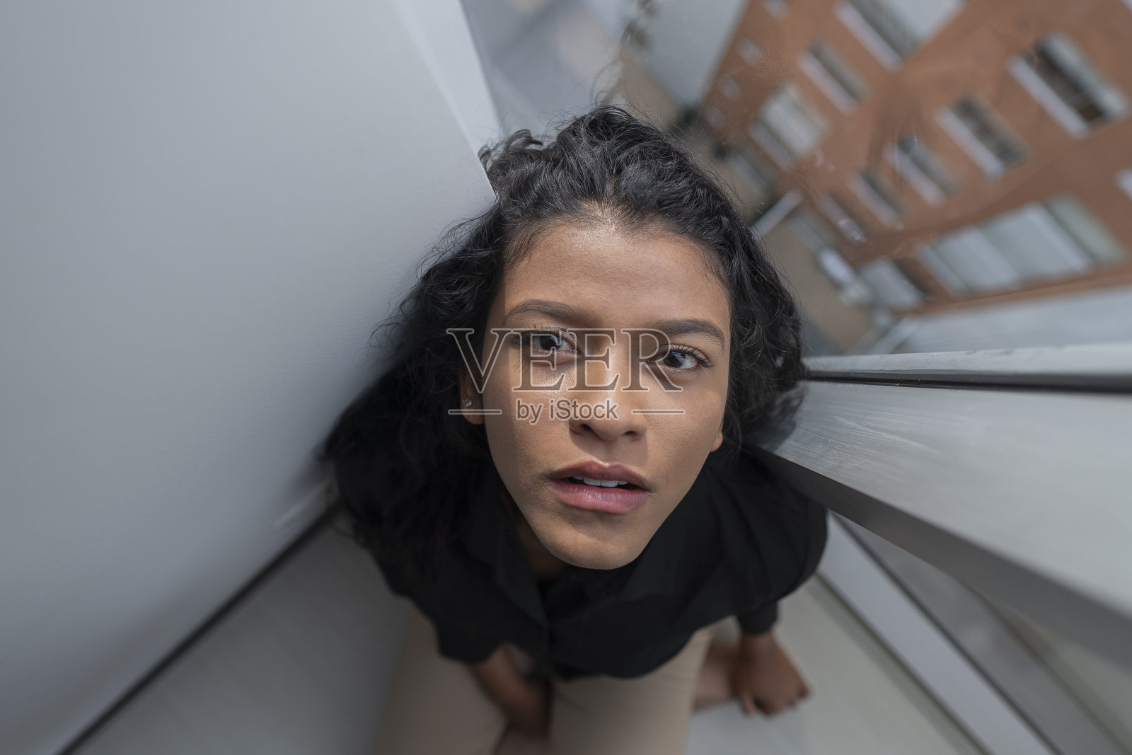 年轻女人在公寓的窗边,带着绝望的表情看着镜头照片摄影图片