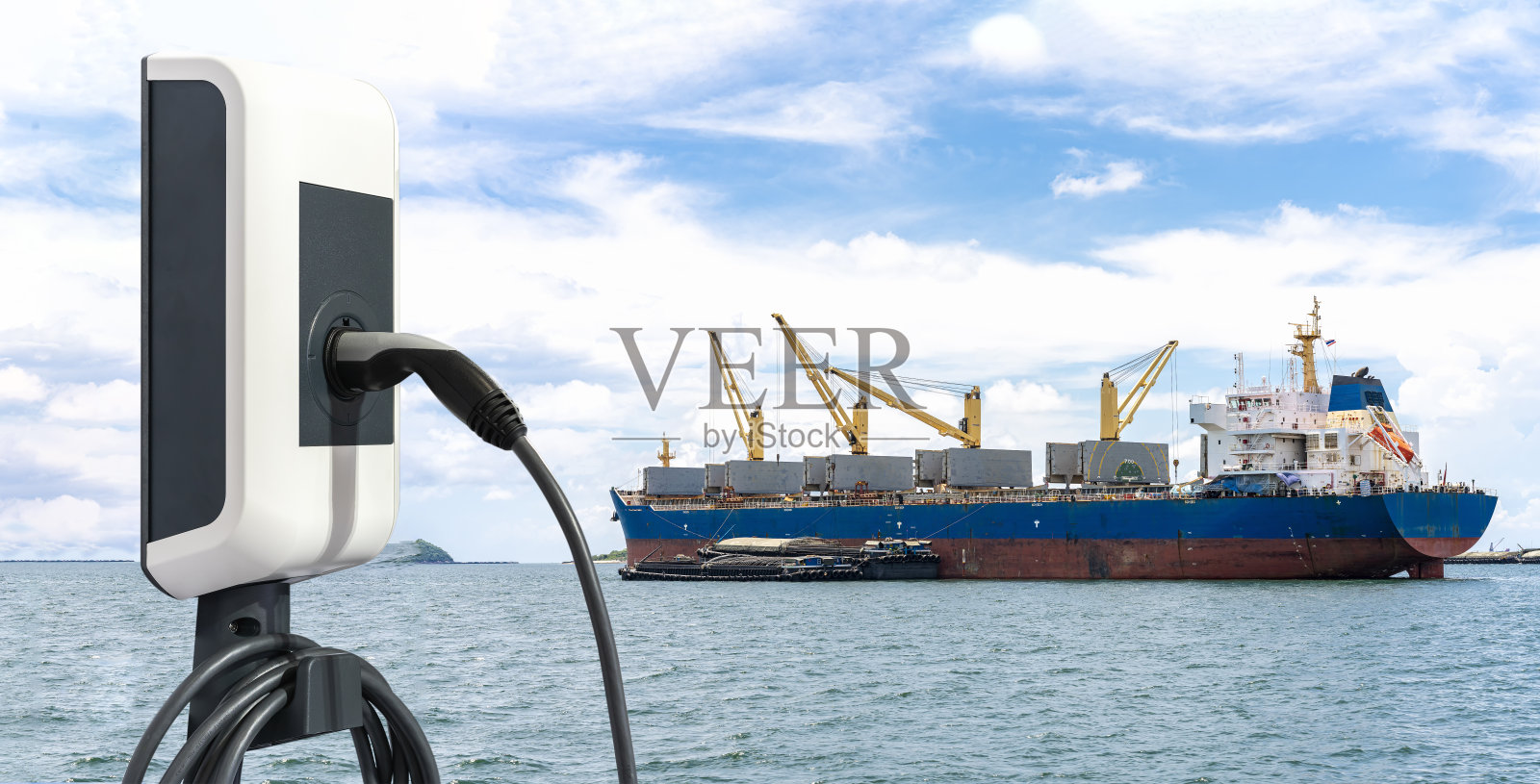 带插头和电源线供应的电站充电器和物流进出口货物的大型货船在阳光明媚的日子里停泊在海上照片摄影图片