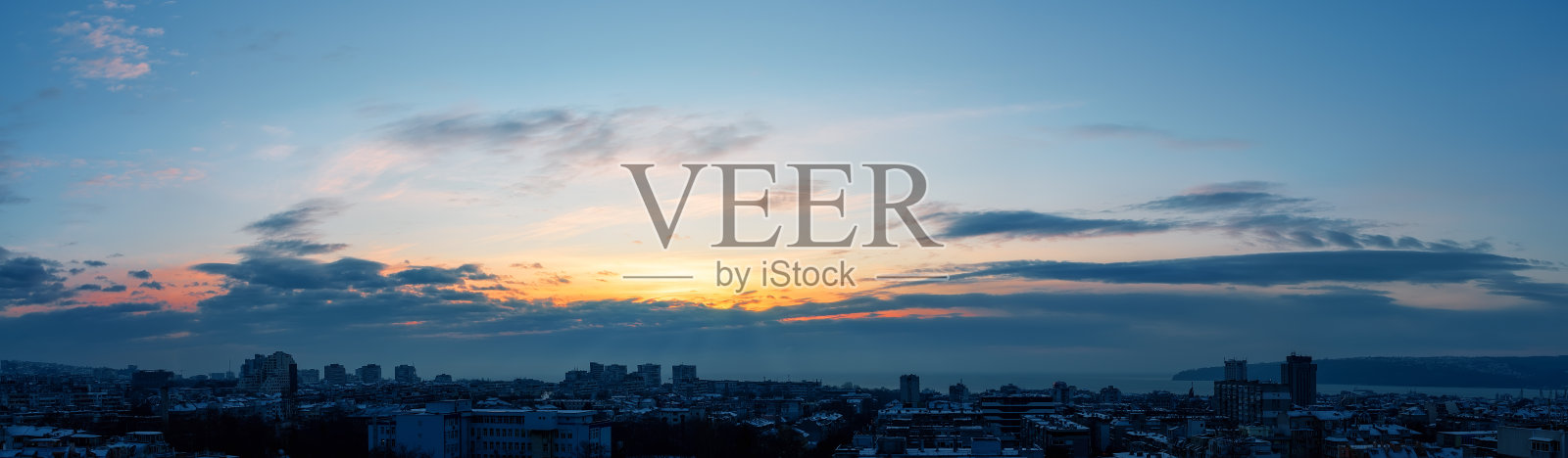 冬天清晨的天空刚刚日出前,在一个海滨小镇。金色的黎明照亮了一座沉睡的城市的天空。城市天际线的全景景观。照片摄影图片