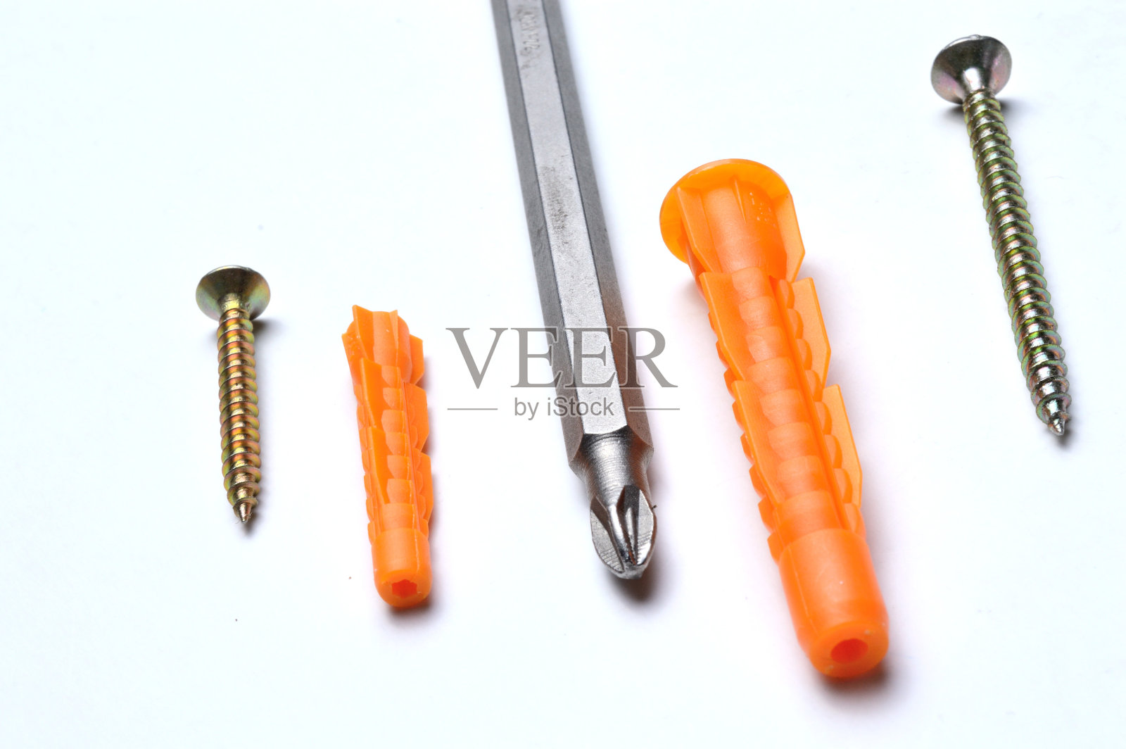 塑料销子,螺丝刀和几个螺丝在一个轻的背景。特写镜头。照片摄影图片