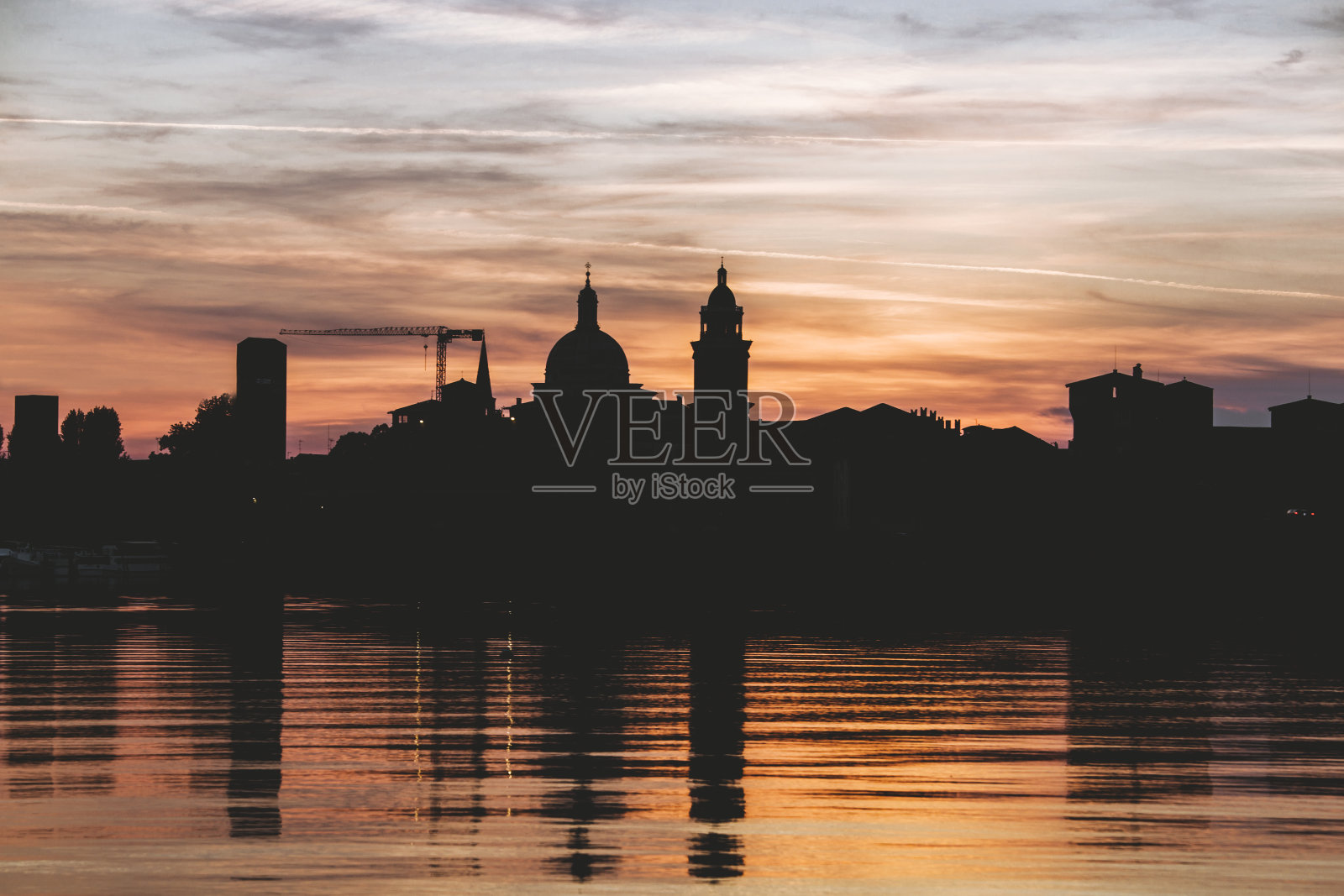 伦巴迪亚,曼托瓦人的剪影映在日落时的明乔湖中照片摄影图片