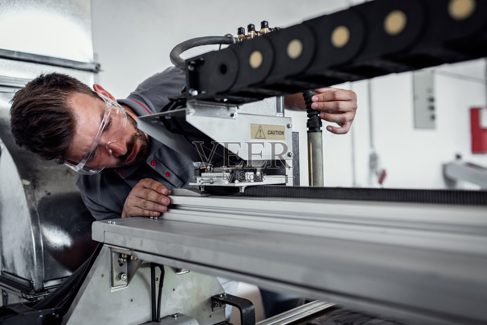 年轻工程师在金属加工车间安装等离子切割机。照片摄影图片