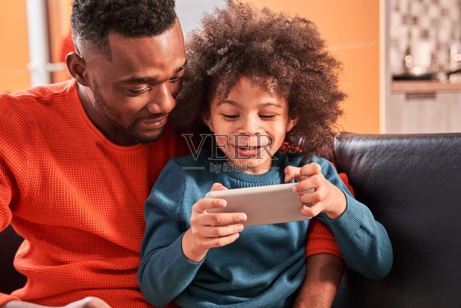 父亲和儿子在家看智能手机上的应用程序照片摄影图片