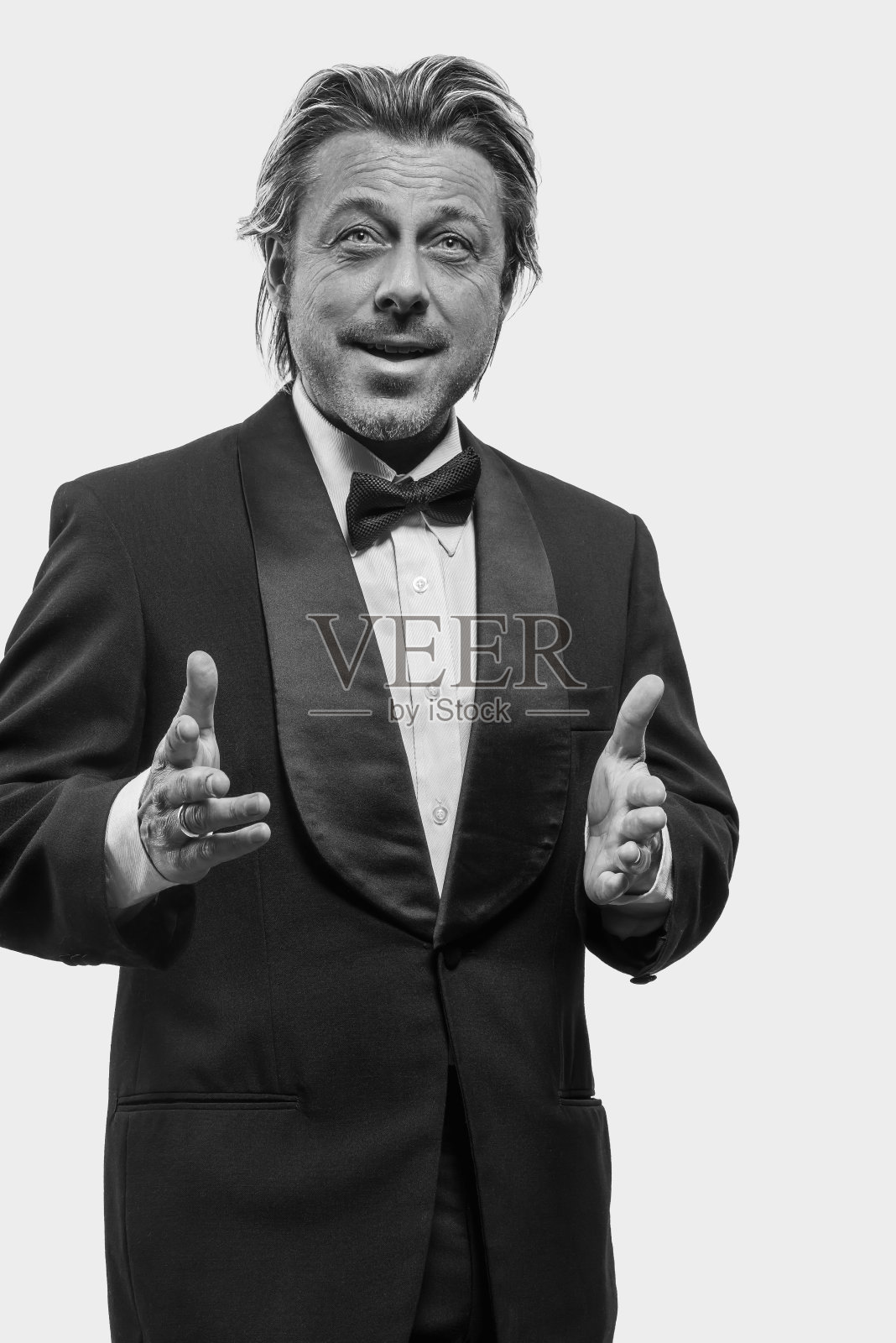 白墙前穿着燕尾服的滑稽男人。黑白照片。照片摄影图片