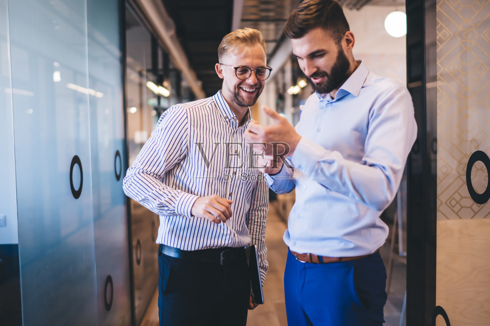 快乐的白种男同事喜欢在闲暇时间一起讨论有趣的故事和大笑,愉快的男人使用智能手机浏览器网络友好的工作环境照片摄影图片