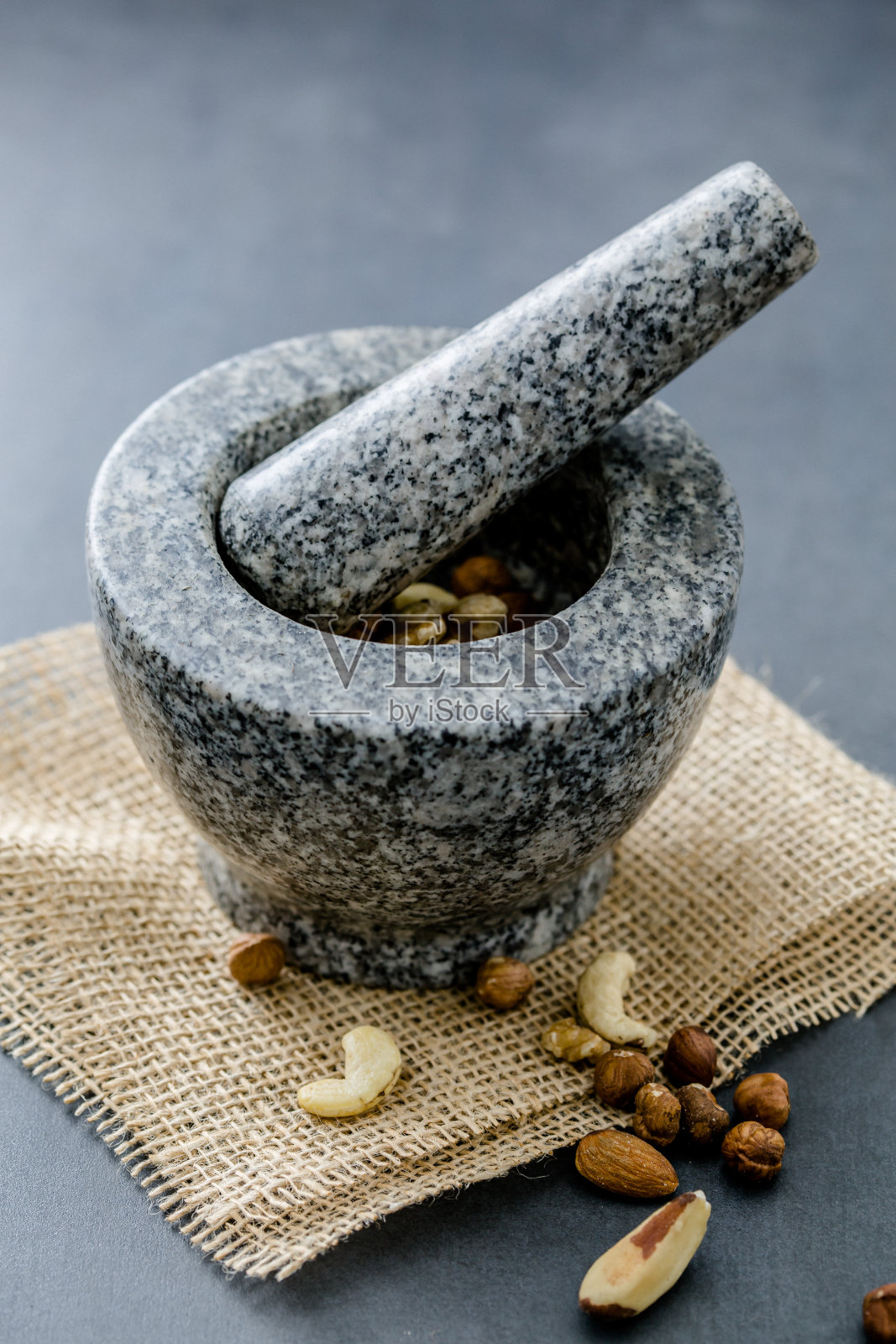 在石制的工作台上,杵着研钵。榛子、巴西坚果、杏仁和腰果都经过加工。照片摄影图片