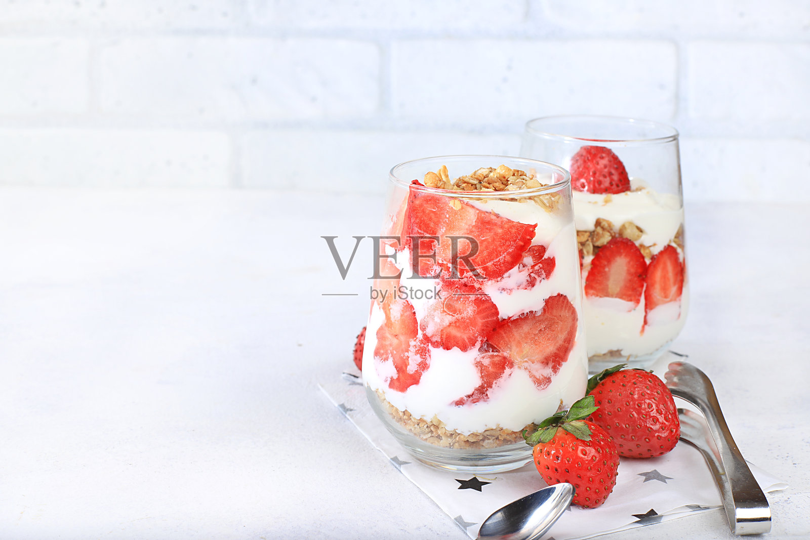 鲜亮的桌子上放着草莓酸奶、浆果和什锦麦片,还有水果沙拉。有用的早餐和配料。健康天然的食品理念、生活方式、儿童食品、选择性关注、照片摄影图片