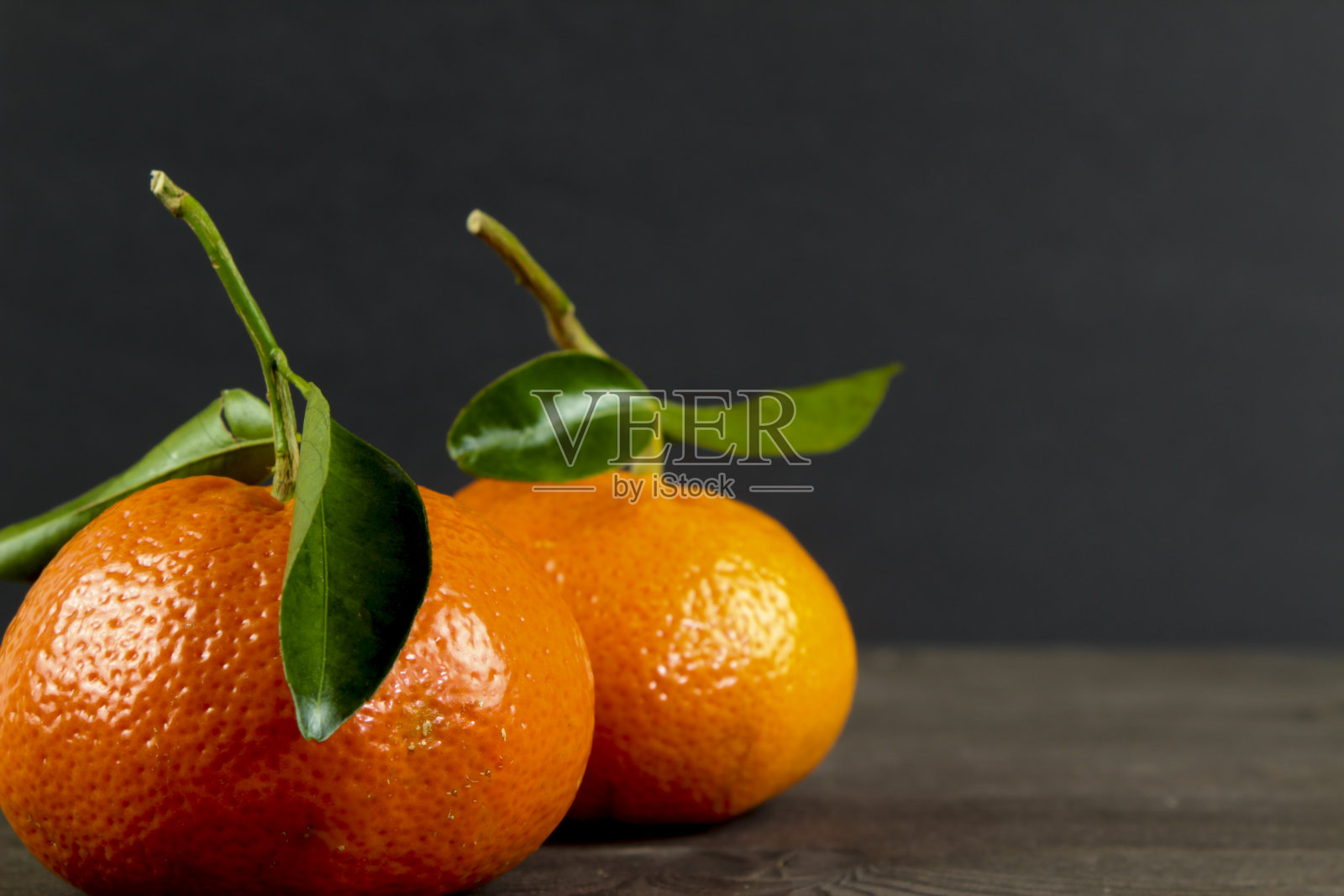 黑色背景下的两个绿叶子的橘子照片摄影图片