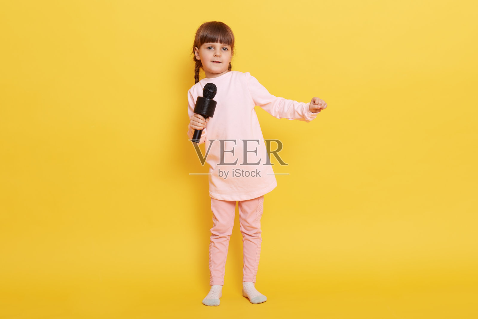 欧洲小女孩拿着麦克风唱歌,看着镜头,在卡拉ok唱歌,表演,制作节目,安排音乐会,小歌手表演。照片摄影图片