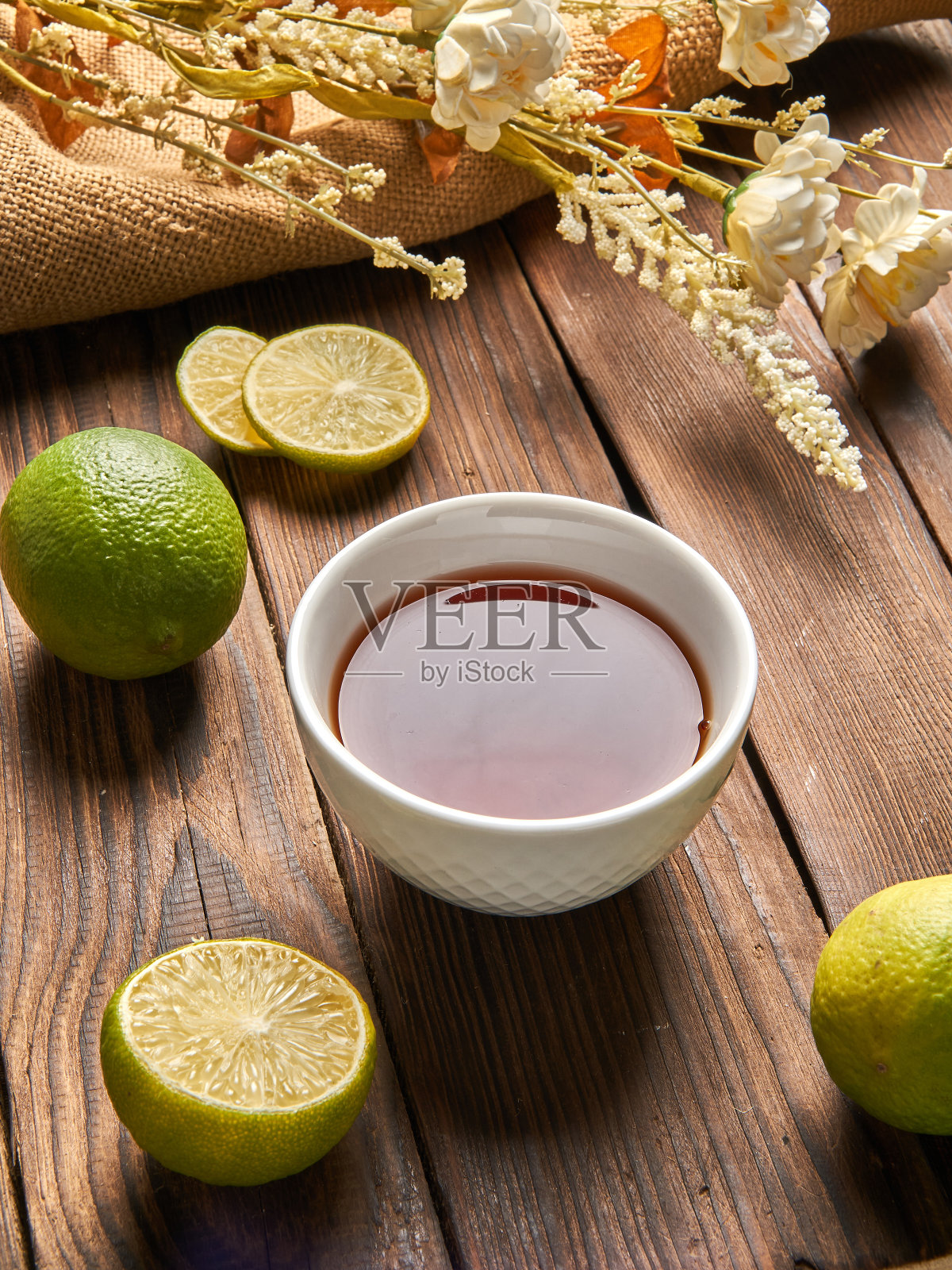 茶和酸橙放在木质的背景上,旁边是花照片摄影图片