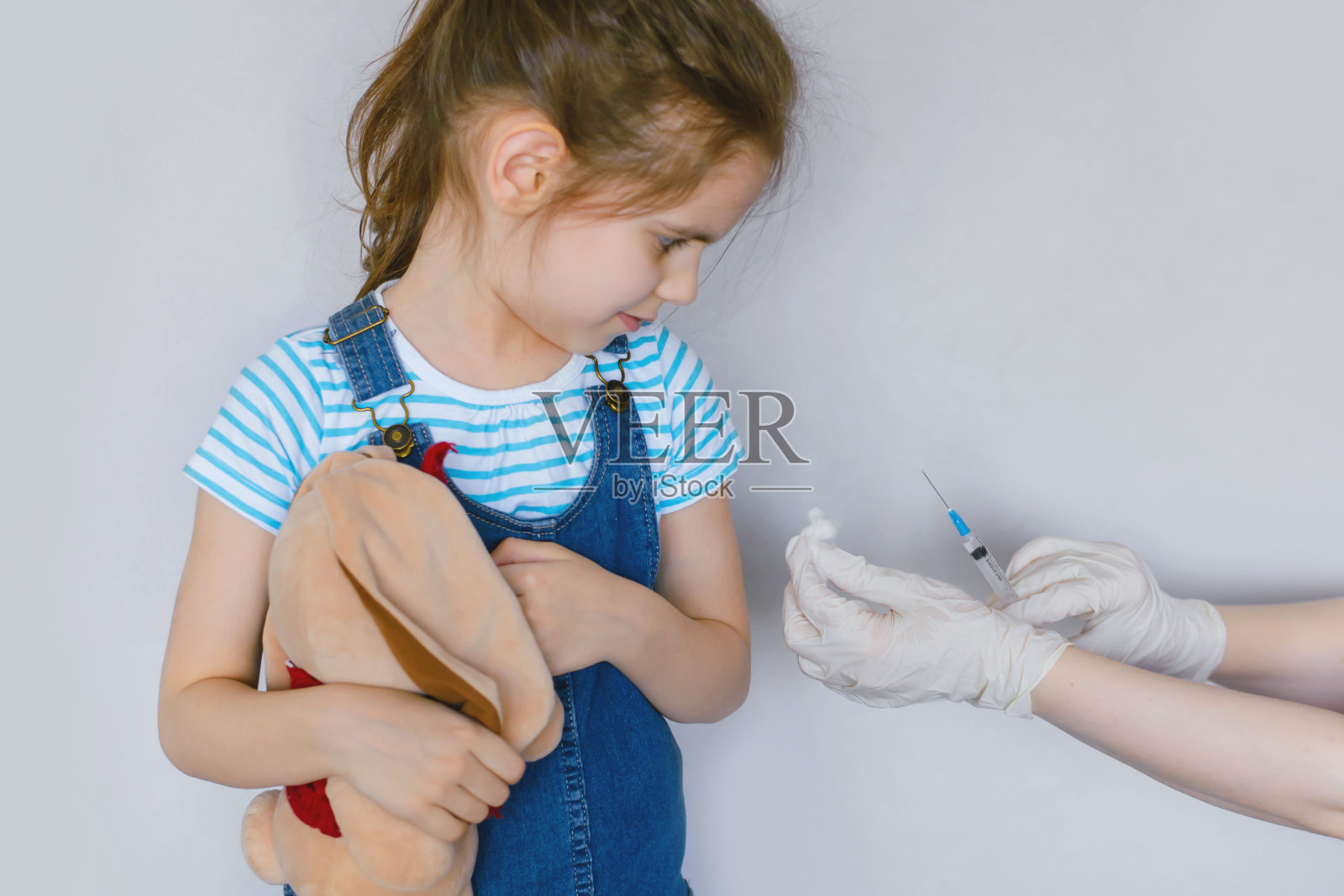 小女孩接种疫苗在工作室隔离白色。大规模接种Covid-19疫苗。照片摄影图片