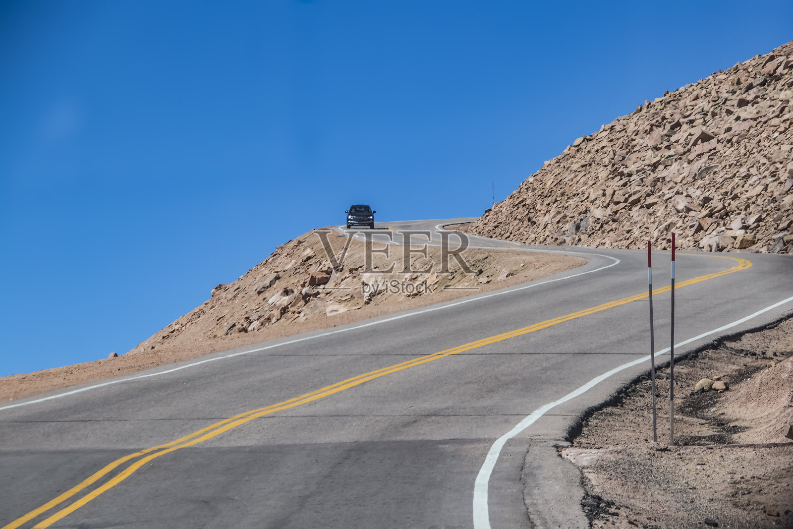 在险峻的山路上,汽车在急转弯和陡坡中转弯,后面是蓝天照片摄影图片