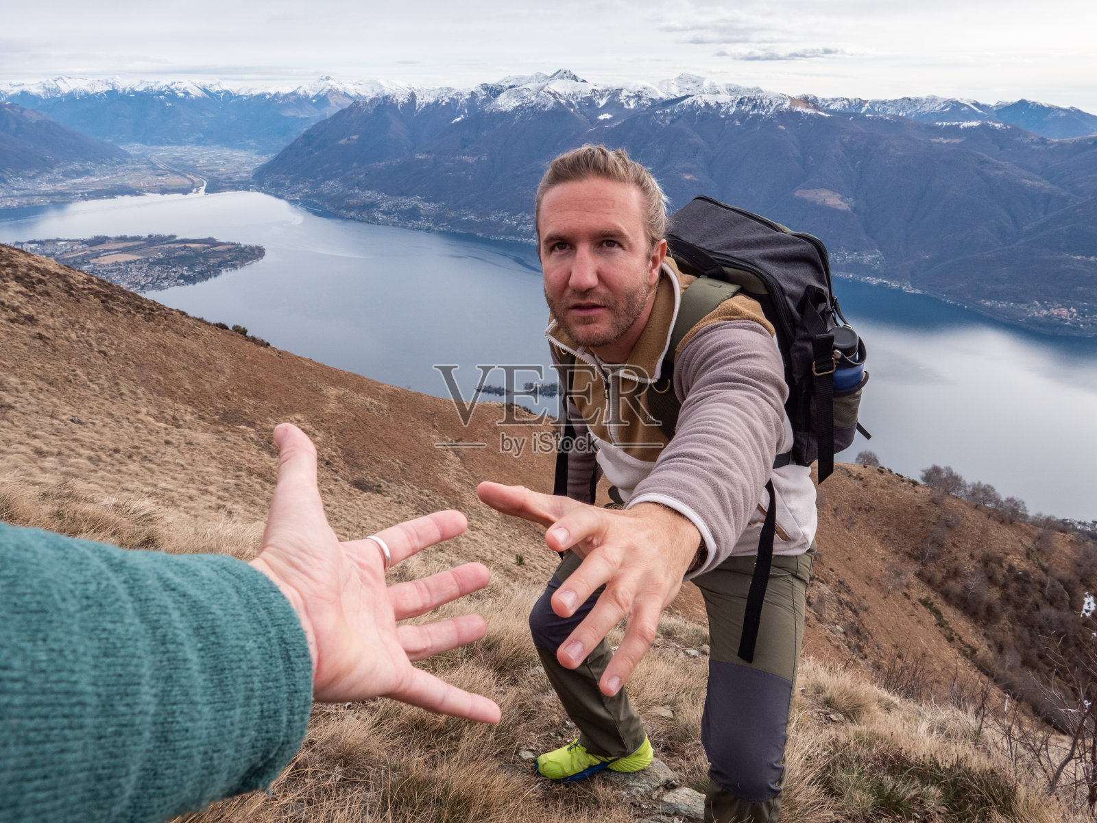 在山顶上,徒步者伸出手向队友求救,以便到达山顶照片摄影图片