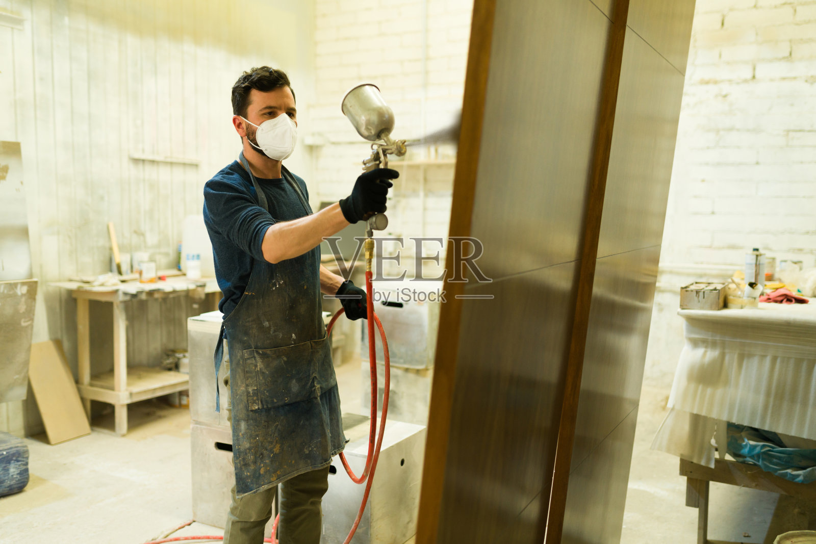 一名男性工人正在粉刷一扇棕色的门照片摄影图片