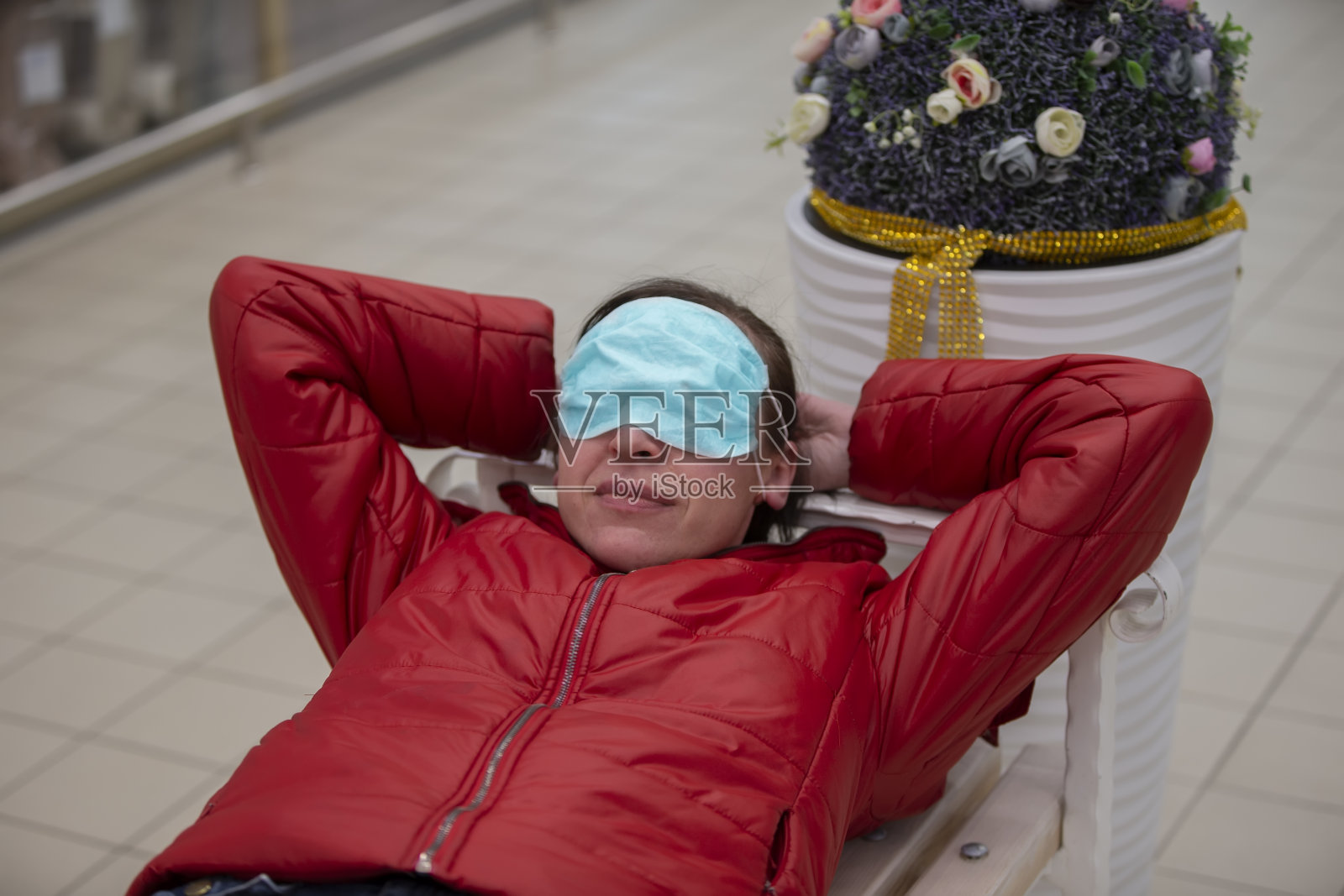 这名妇女戴上医用口罩,躺下休息。来自冠状病毒疫情的疲劳。照片摄影图片