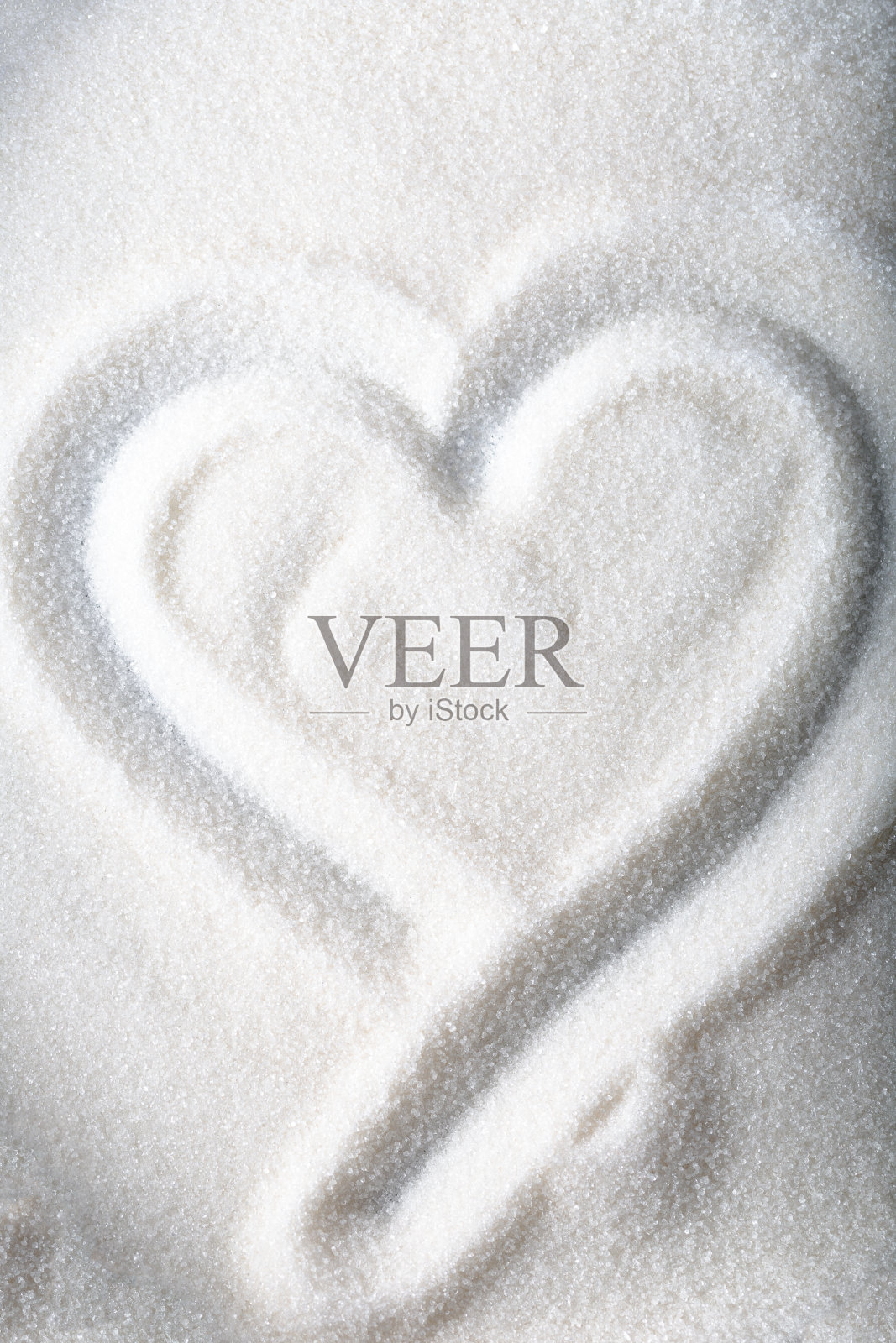 心形在砂糖的背景上画上白糖。照片摄影图片