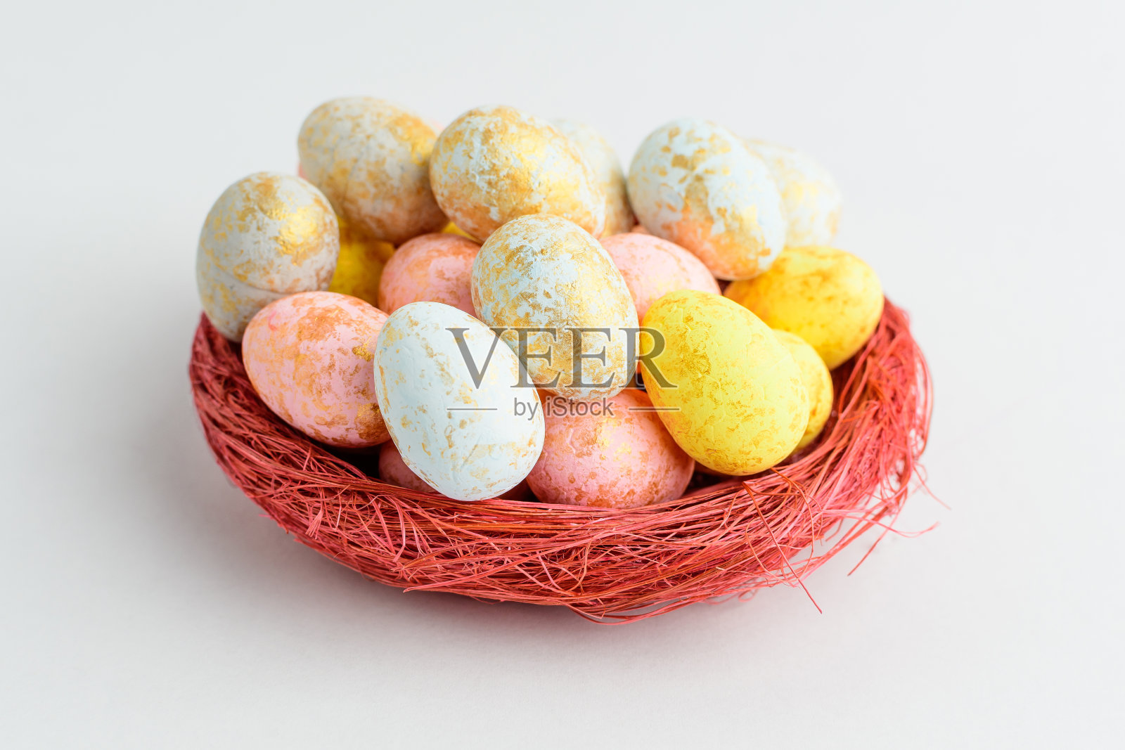 涂有巧克力的复活节彩蛋和糖果分别放在一个红色的小篮子里,放在一张白色的桌子上,是给孩子们吃的可口的甜甜点照片摄影图片