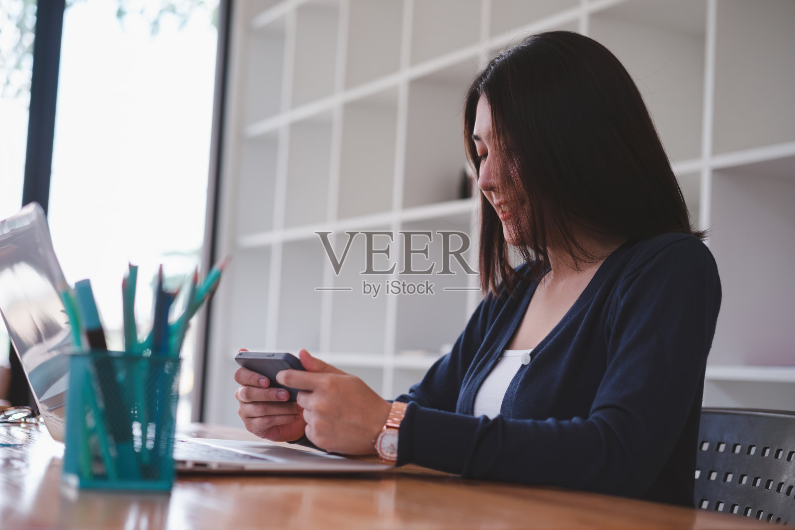 年轻的亚洲女性工人有一个休息和使用智能手机工作后。照片摄影图片