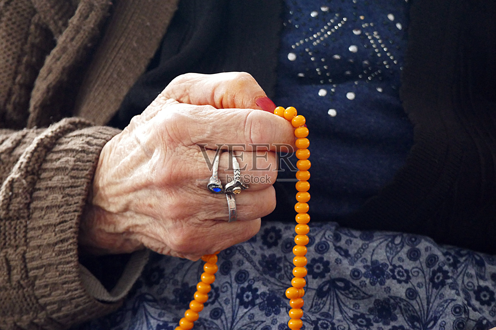 穆斯林老妇人手里拿着念珠在朝拜,照片摄影图片