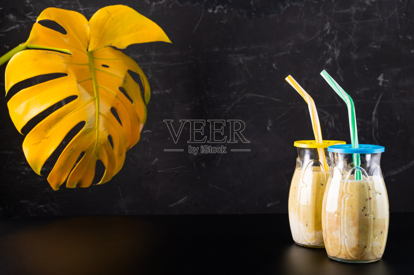 两杯加一杯鸡尾酒。黑色背景上有吸管的鸡尾酒。怪物在后面。照片摄影图片