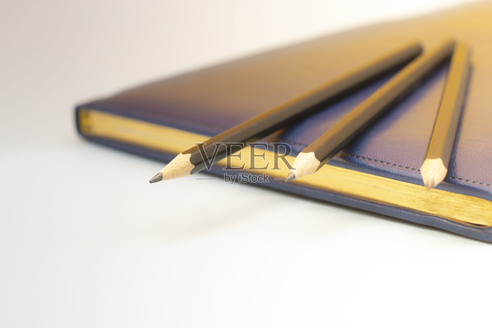 深蓝色的皮革笔记本和三支铅笔。为商务会议做准备。经营理念照片摄影图片